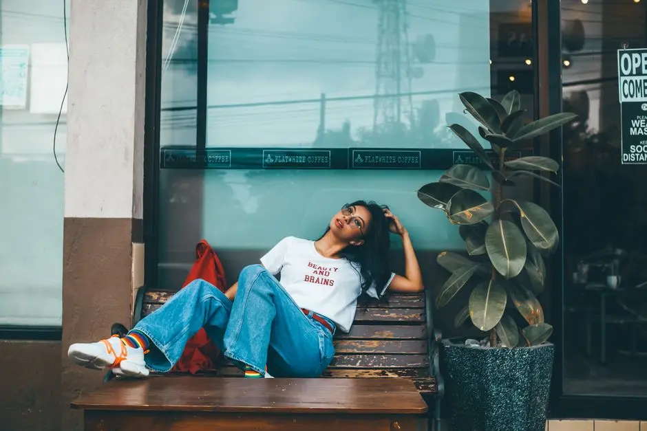 Pemuda di Lsolok memadukan kaus thrift dengan celana jeans sobek di kafe sederhana
